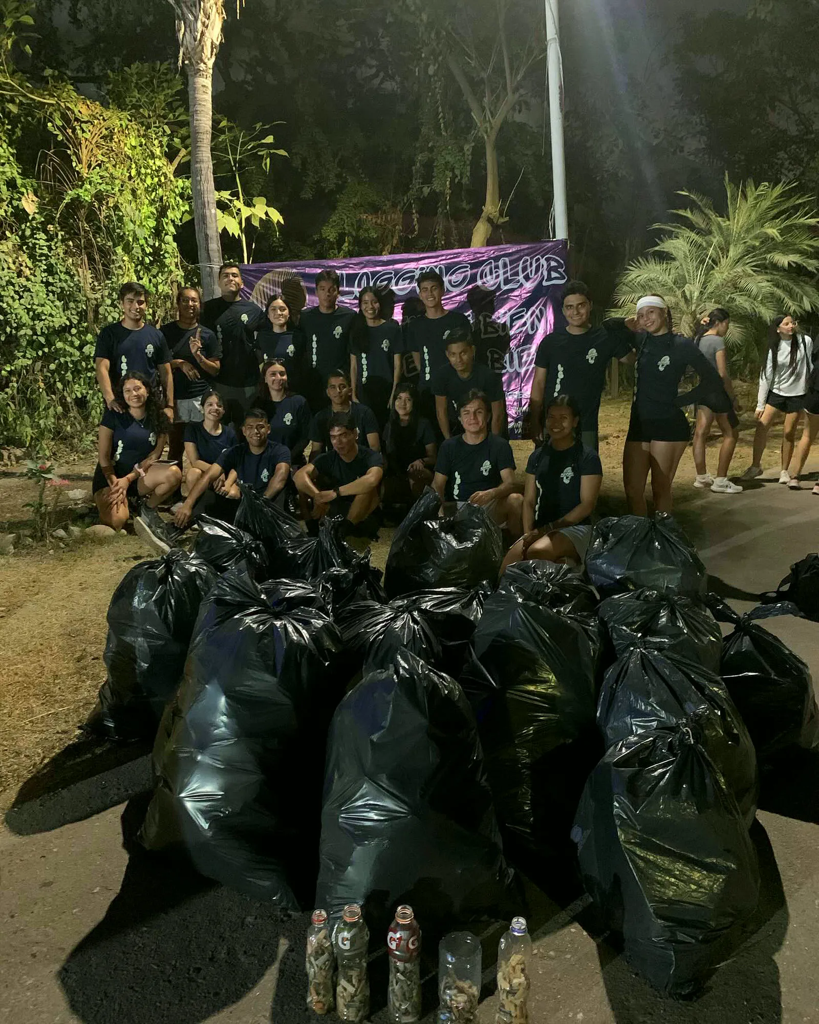 Grupo detrás de una montaña de bolsas negras de basura