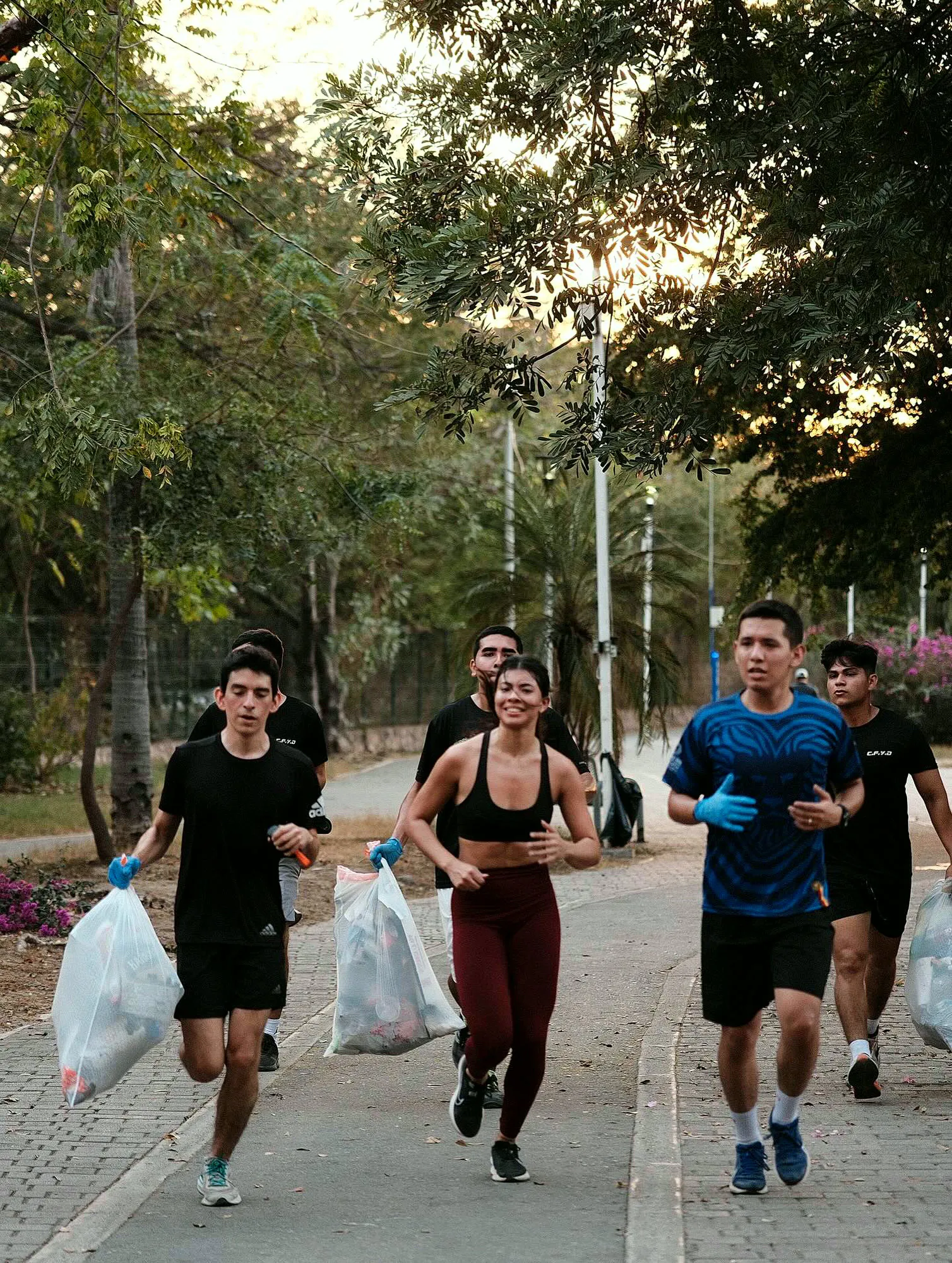 Grupo de runners con guantes azules y bolsas de basura corriendo en el Parque Lineal